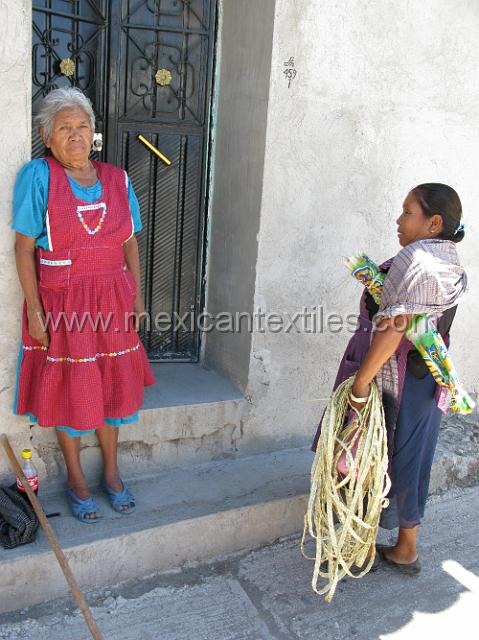 totolzintla_nahuatl05.JPG - Here we see two women , one on the left wearing the more traditional peasant wear and on the right more modern dress. Both are palm weavers. On the right the women holds palm braids and under her arm the palm the she is weaving.